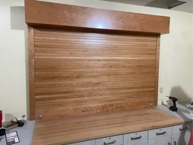 Wooden roll-up cabinet door over a countertop in a kitchen or workspace