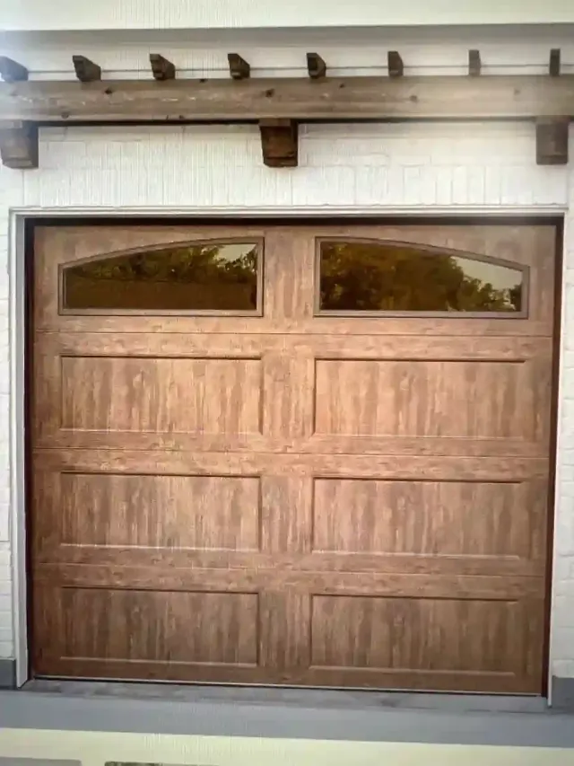 Wooden double garage door with small arched windows in a white stucco wall