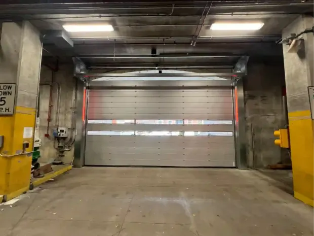Industrial loading dock with closed metal roll-up door and yellow safety barriers
