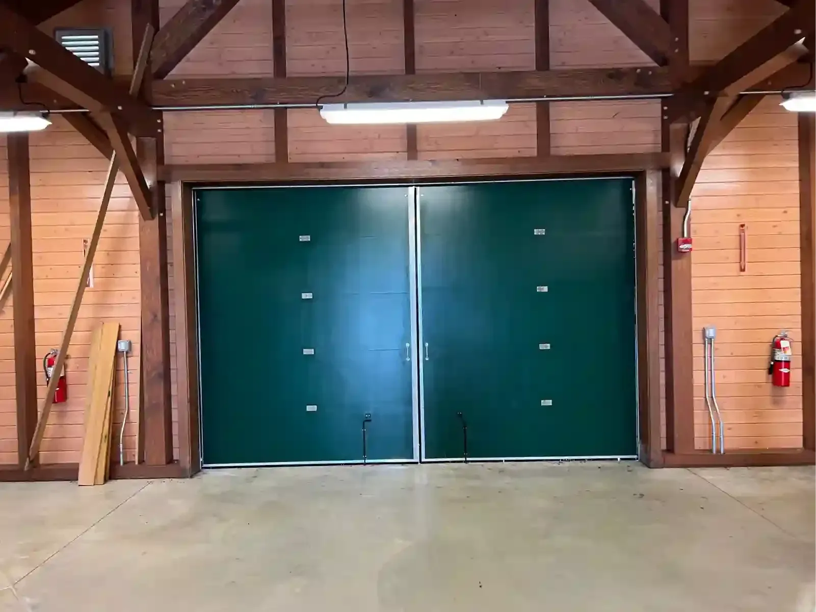 Wooden barn interior with large teal double doors and a concrete floor.