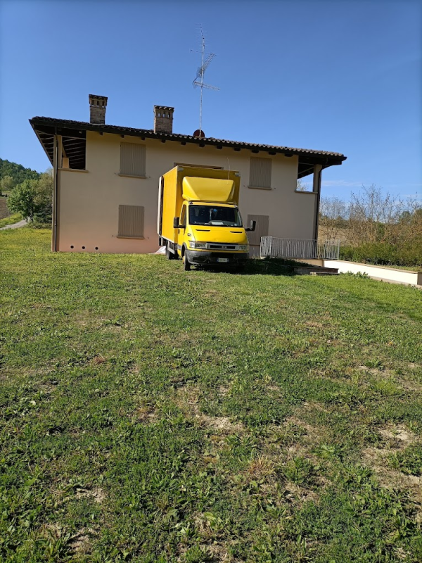 Un camion giallo parcheggiato accanto a una casa beige sotto un cielo azzurro.