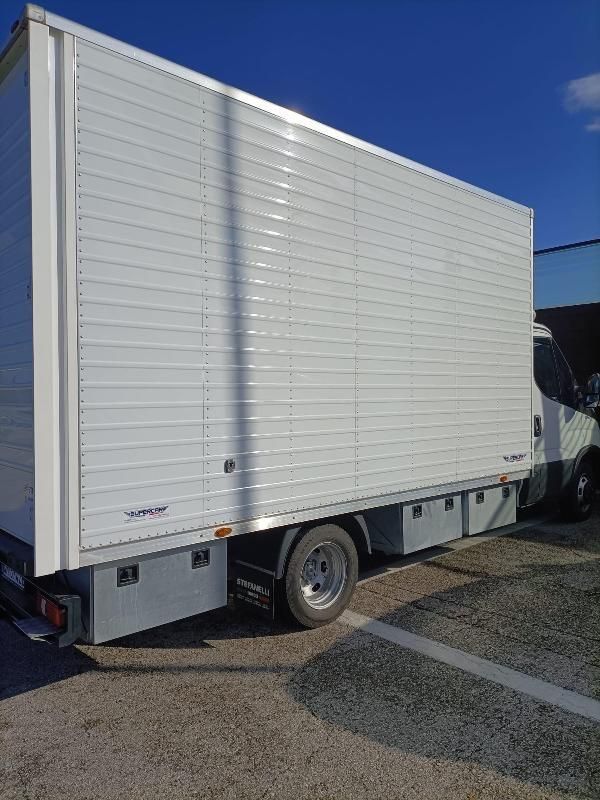 Un furgone bianco parcheggiato in un piazzale sotto un cielo azzurro e limpido.