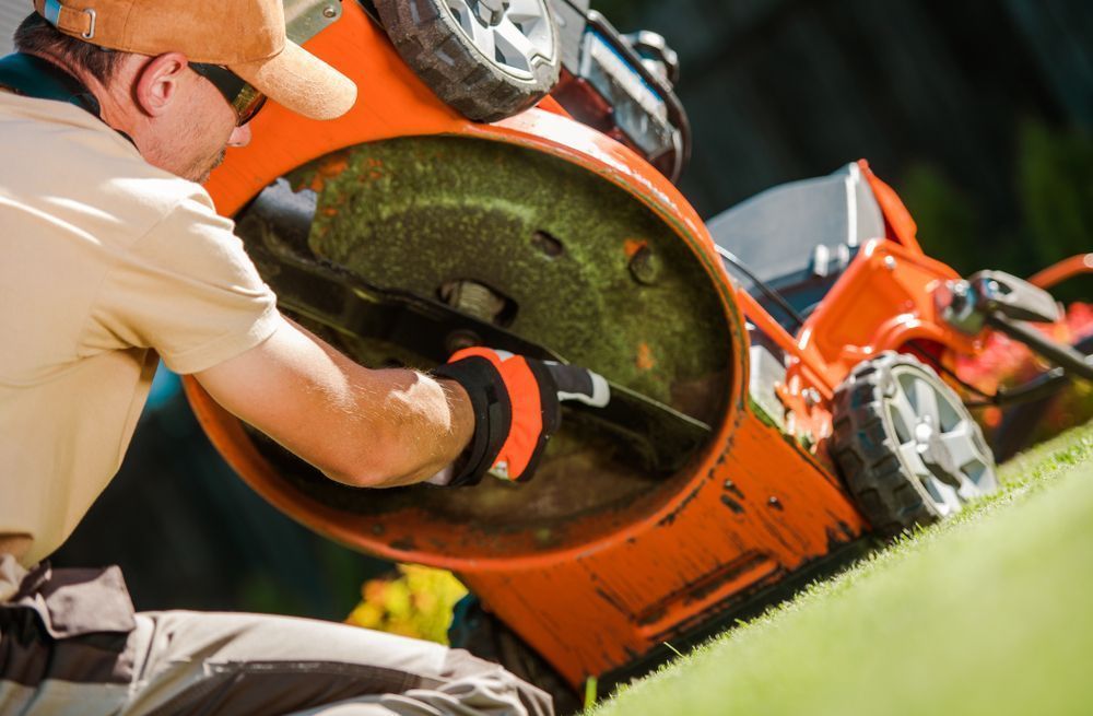 A Man Is Cutting The Grass With An Orange Lawn Mower — Leslie Farm & Garden Machinery In South Grafton, NSW