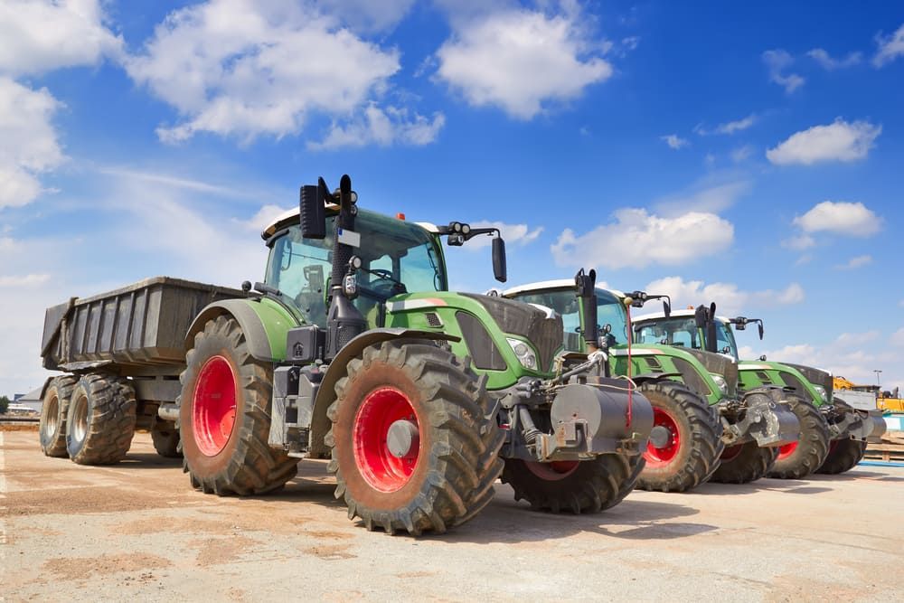 A Row Of Tractors Parked Next To Each Other On A Dirt Road — Leslie Farm & Garden Machinery In South Grafton, NSW