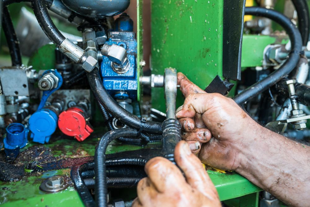 Green Tractor Being Repaired by Worker