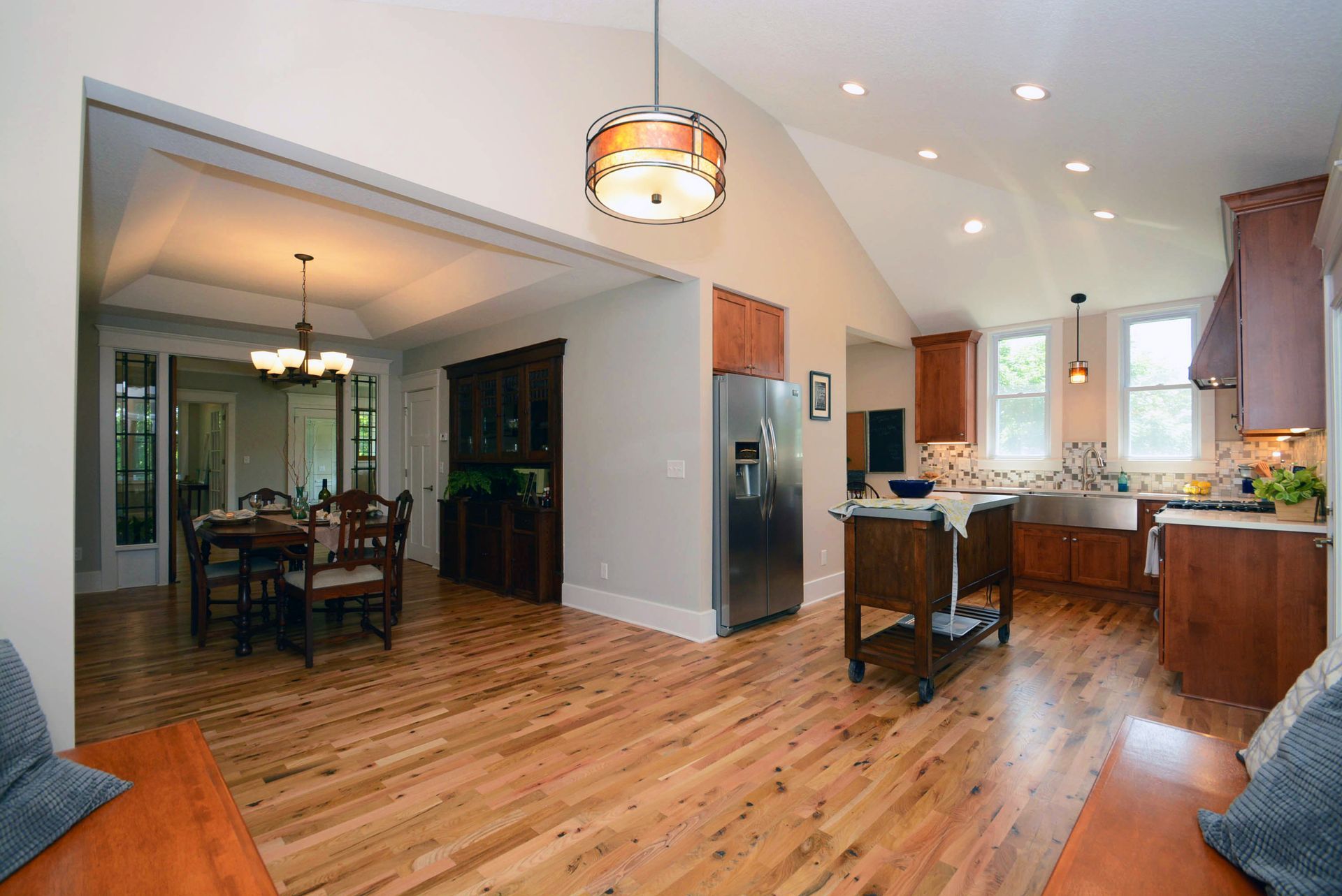 Open-concept kitchen and dining room with wooden floors, stainless steel appliances, and wood cabinetry.