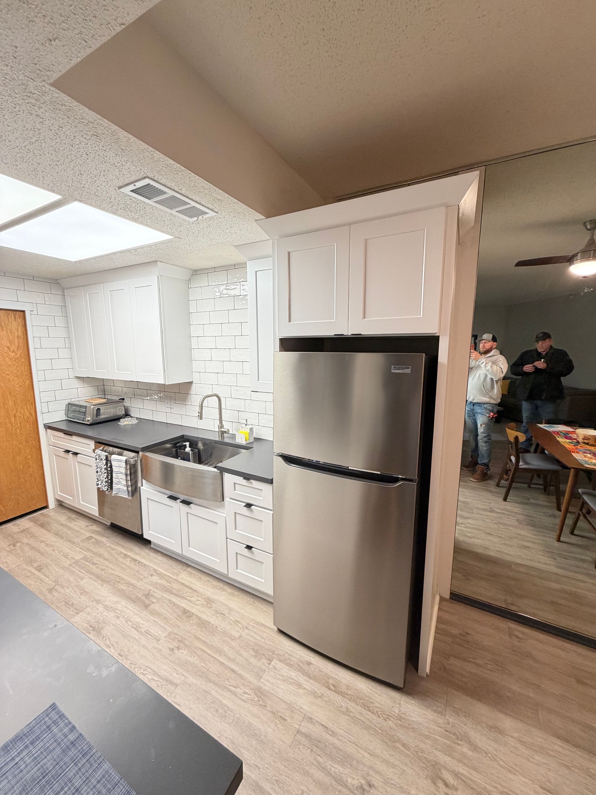 Kitchen with white cabinets, stainless steel appliances, and a mirrored wall.