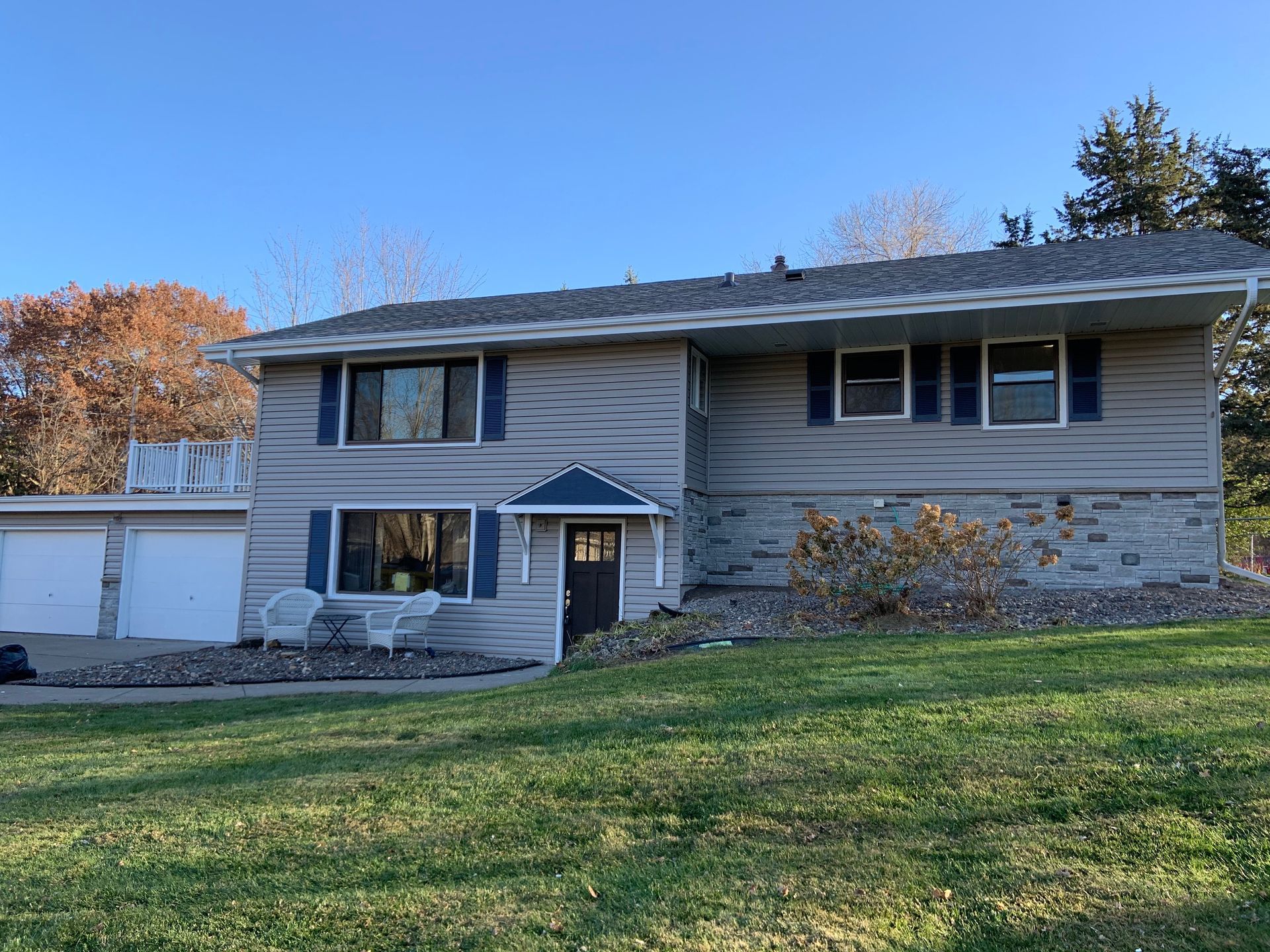 Two-story house with gray siding, blue shutters, and a lawn. Three-car garage on the left.