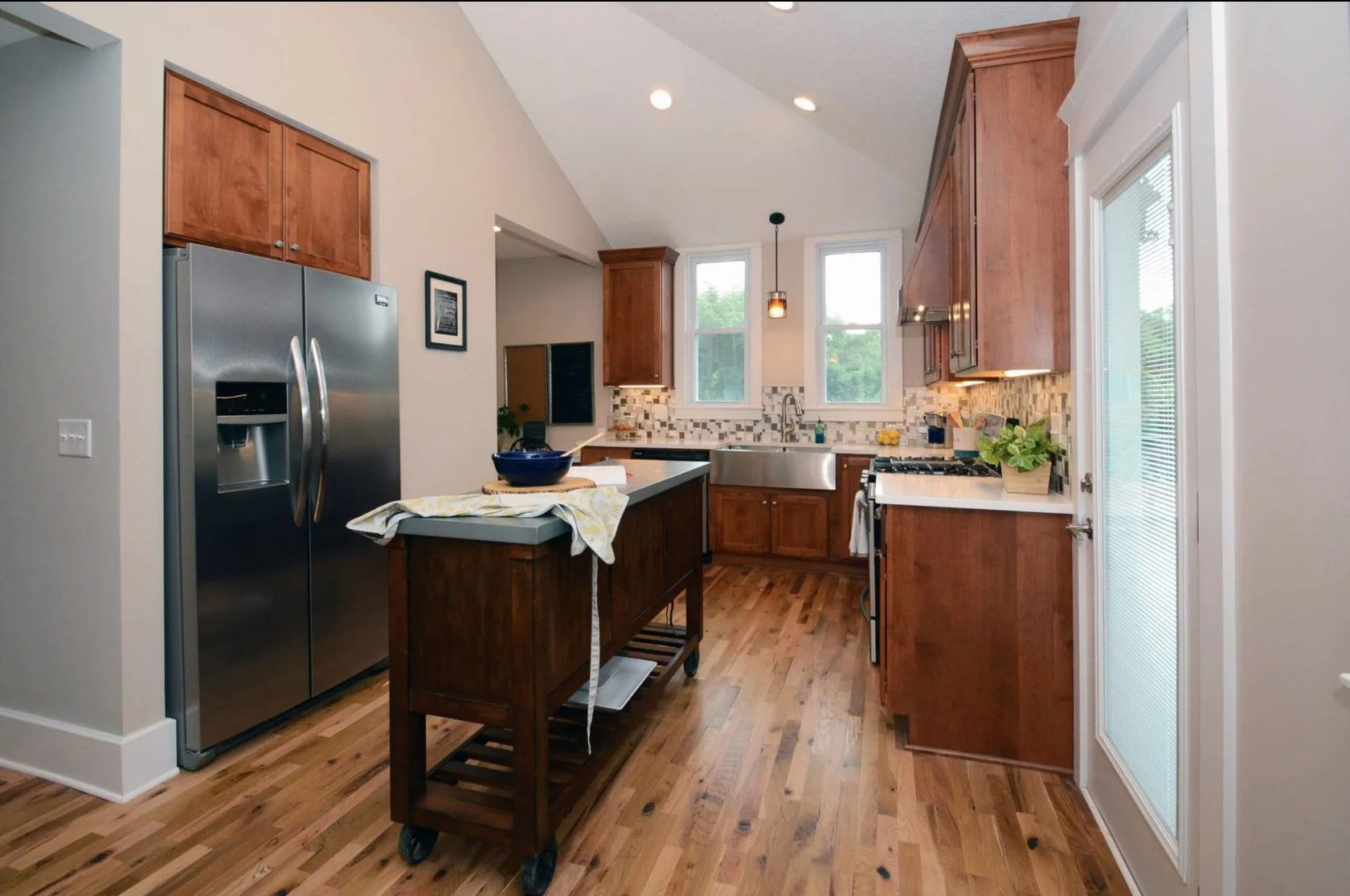 Kitchen with wood cabinets, stainless steel appliances, and island. Natural light floods the room.