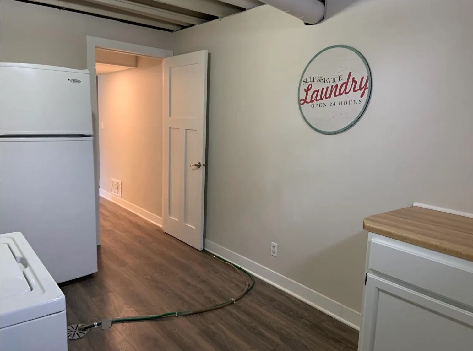 Laundry room with a washing machine, refrigerator, door, and a