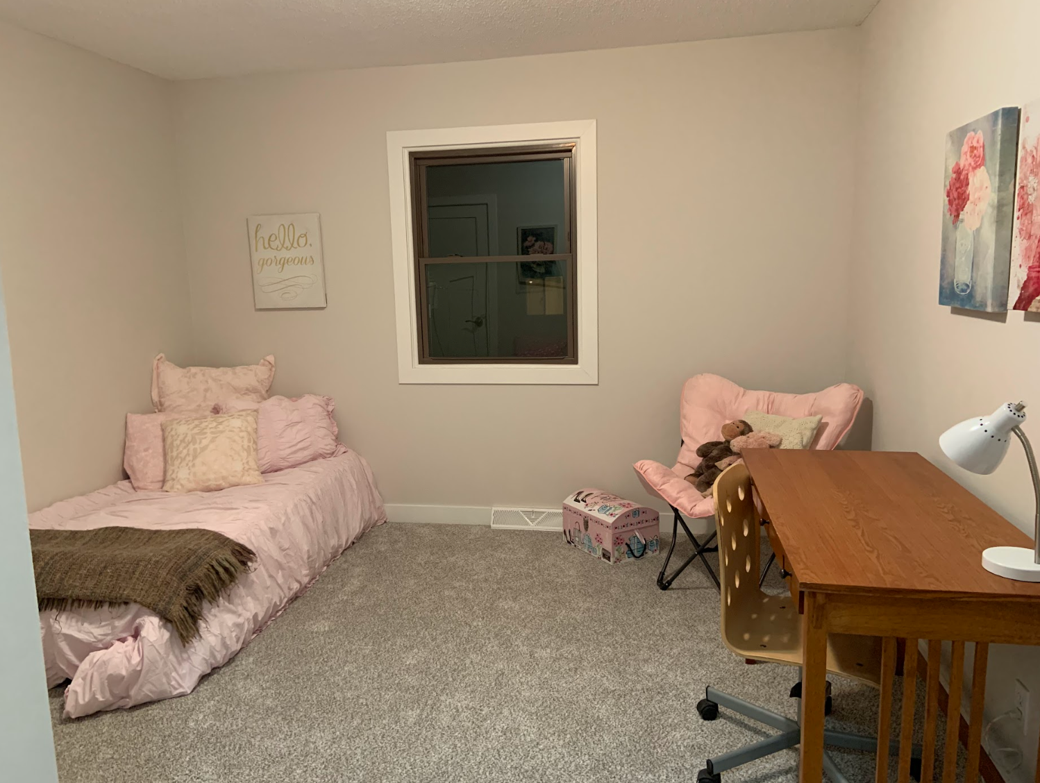 Bedroom with pink bed, chair, desk, window, and gray carpet.