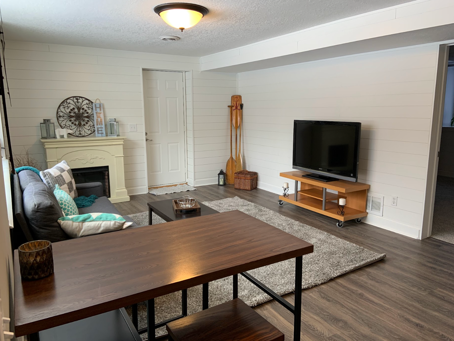Living room with a TV on a wooden stand, a rug, a fireplace, and a dining table.