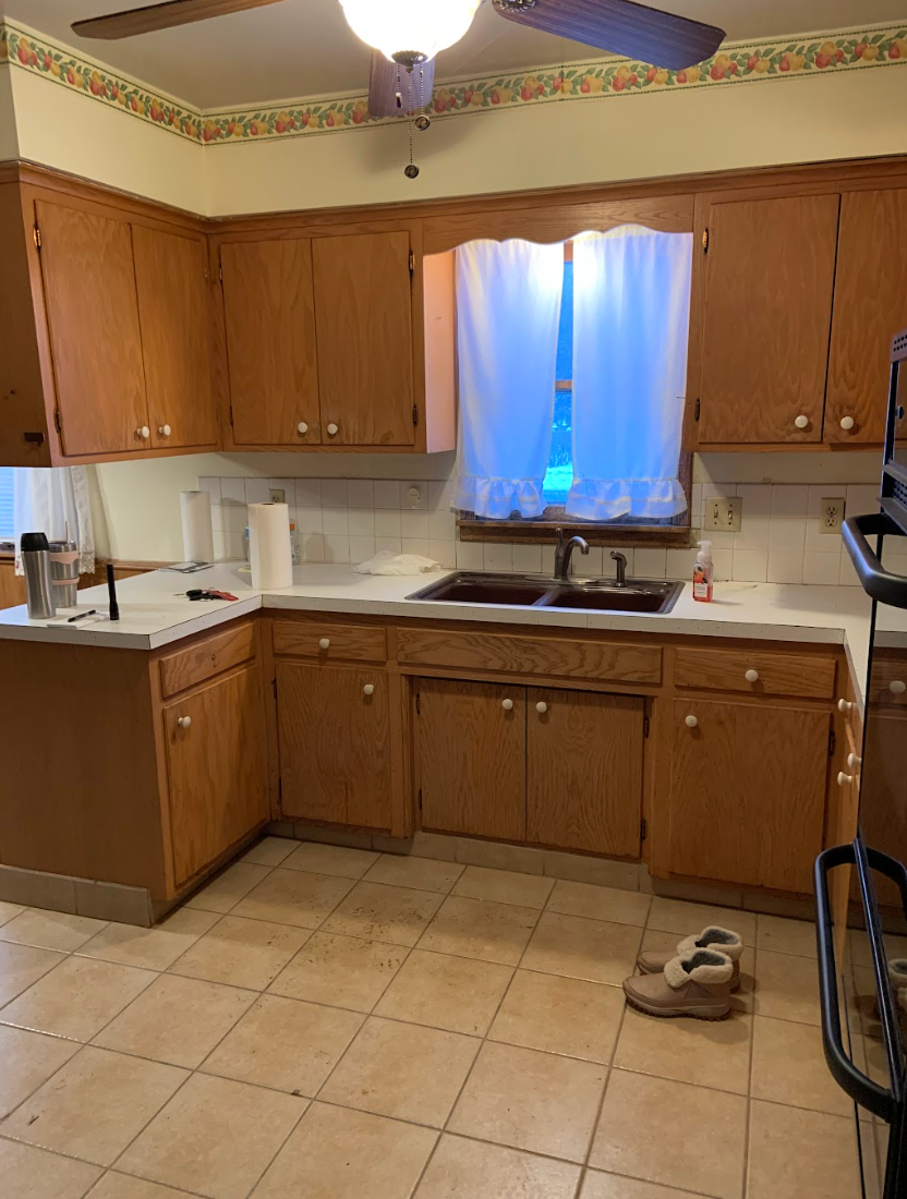 Kitchen with light wood cabinets, white countertops, and tan tile floor.