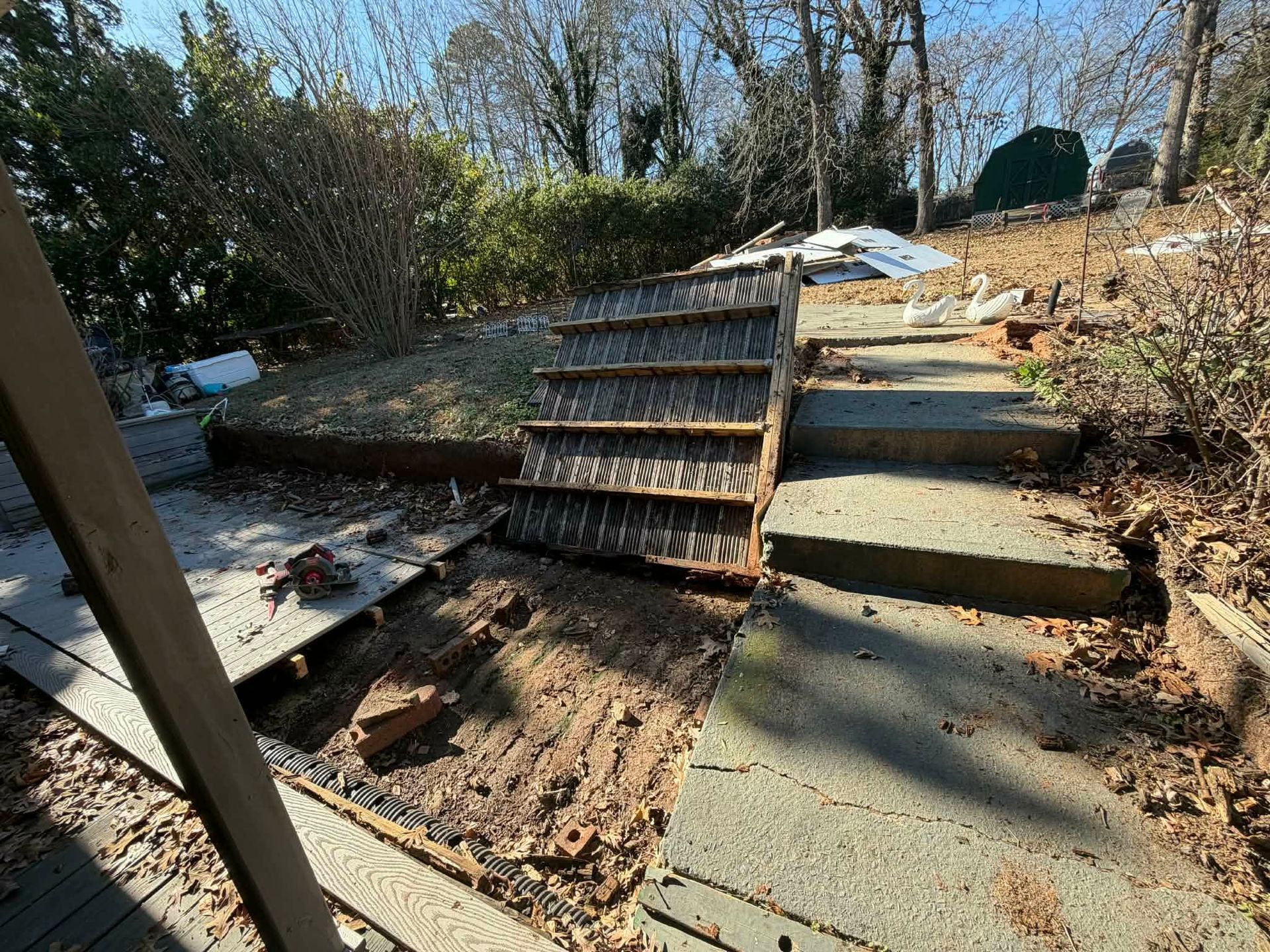 Damaged outdoor steps with broken wooden treads and concrete slabs in a wooded area