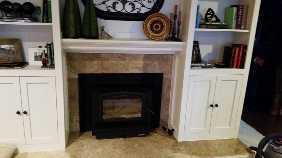 Living room fireplace flanked by white built-in cabinets and shelves with books and decor.
