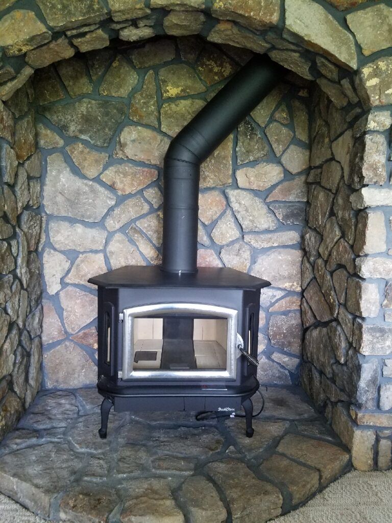 Black Wood Stove In Stone Alcove.
