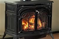 Black cast-iron fireplace stove with bright flames burning inside in a room