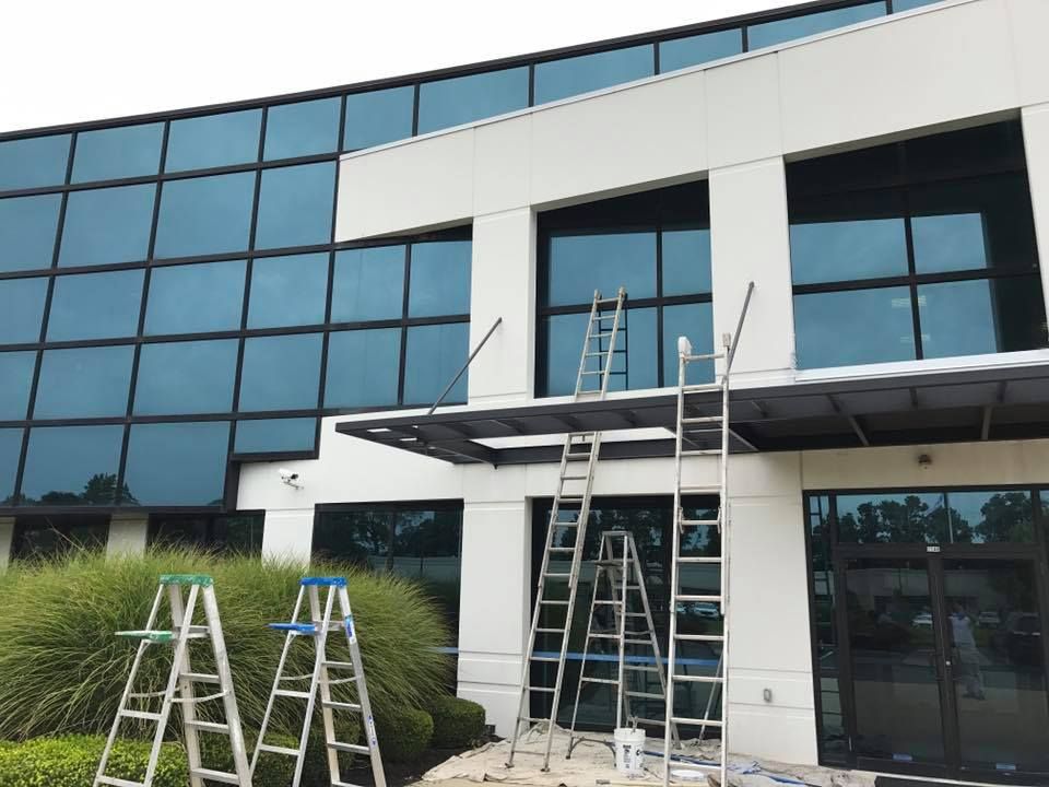 A building is being painted with ladders in front of it