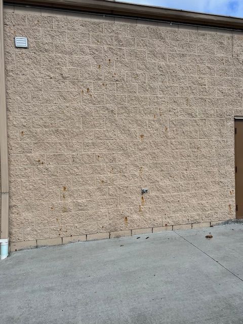 A brick building with a door and a concrete driveway in front of it.