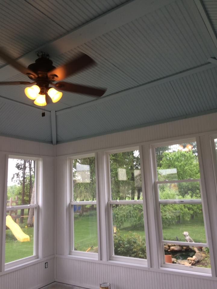 A room with a ceiling fan and lots of windows