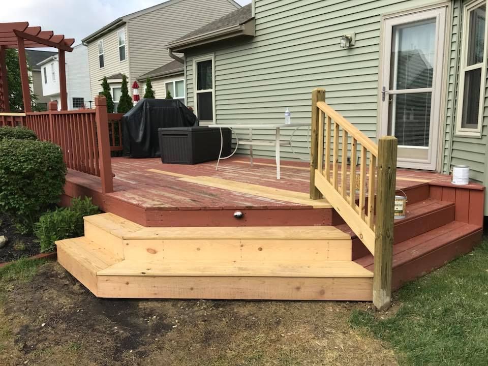 A wooden deck with stairs is in front of a house.