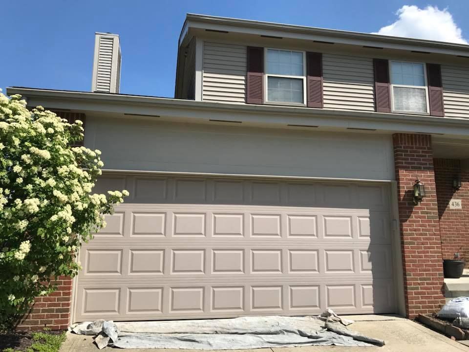 A house with a garage door that is being painted.
