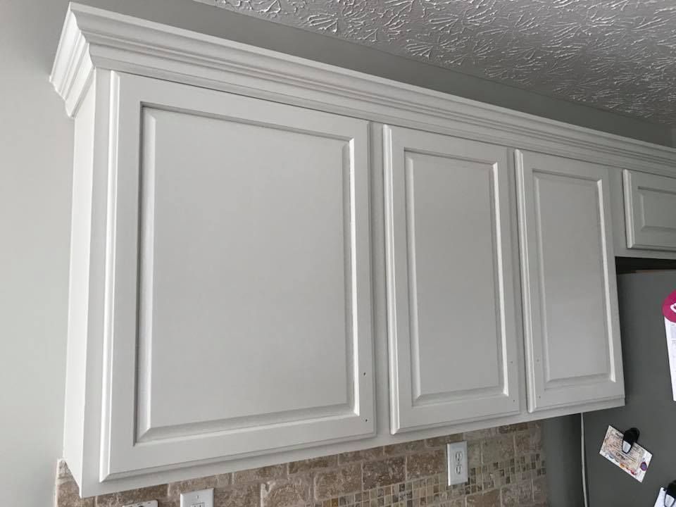 A kitchen with white cabinets and a stainless steel refrigerator.