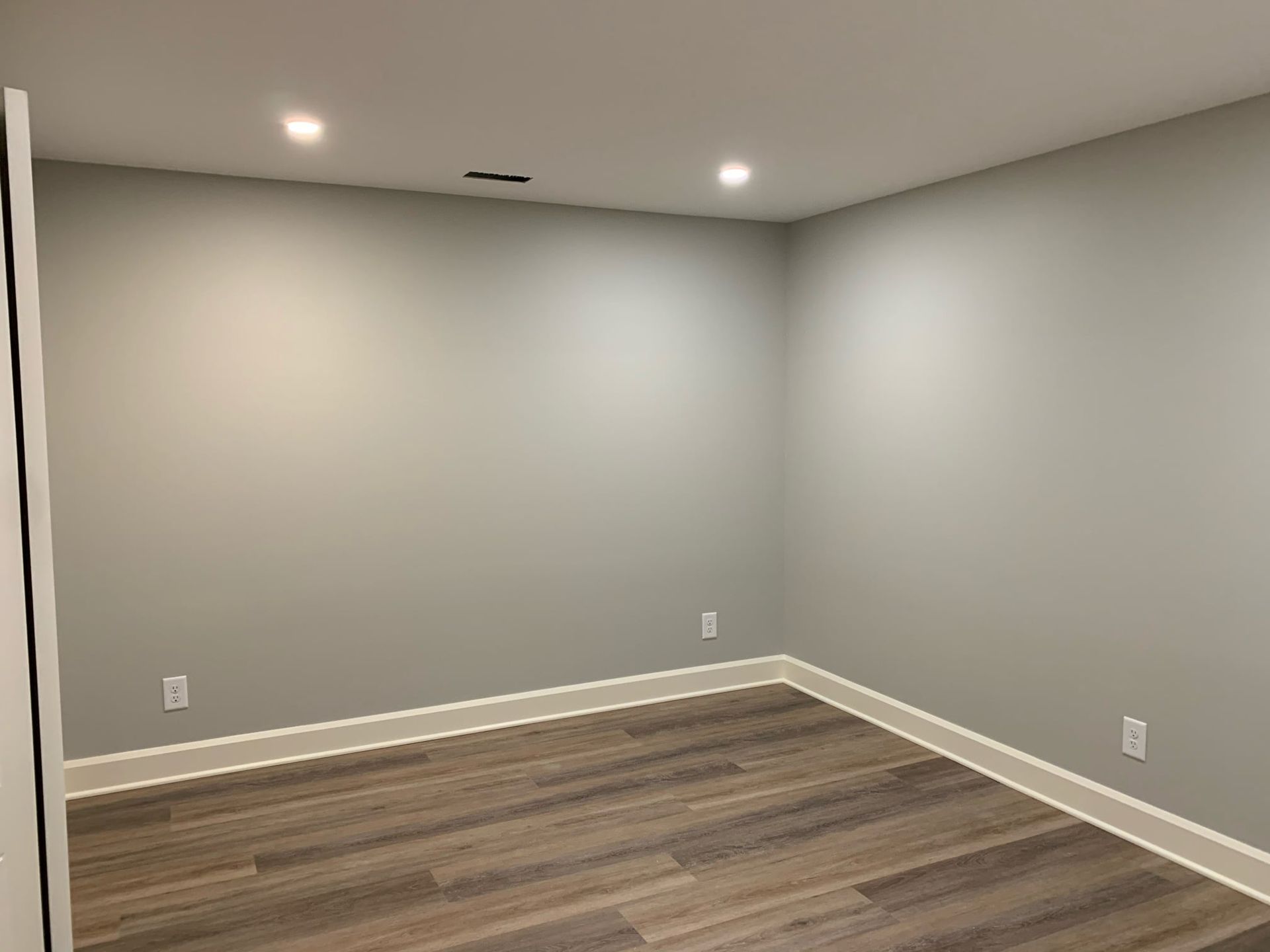 An empty room with a wooden floor and gray walls.