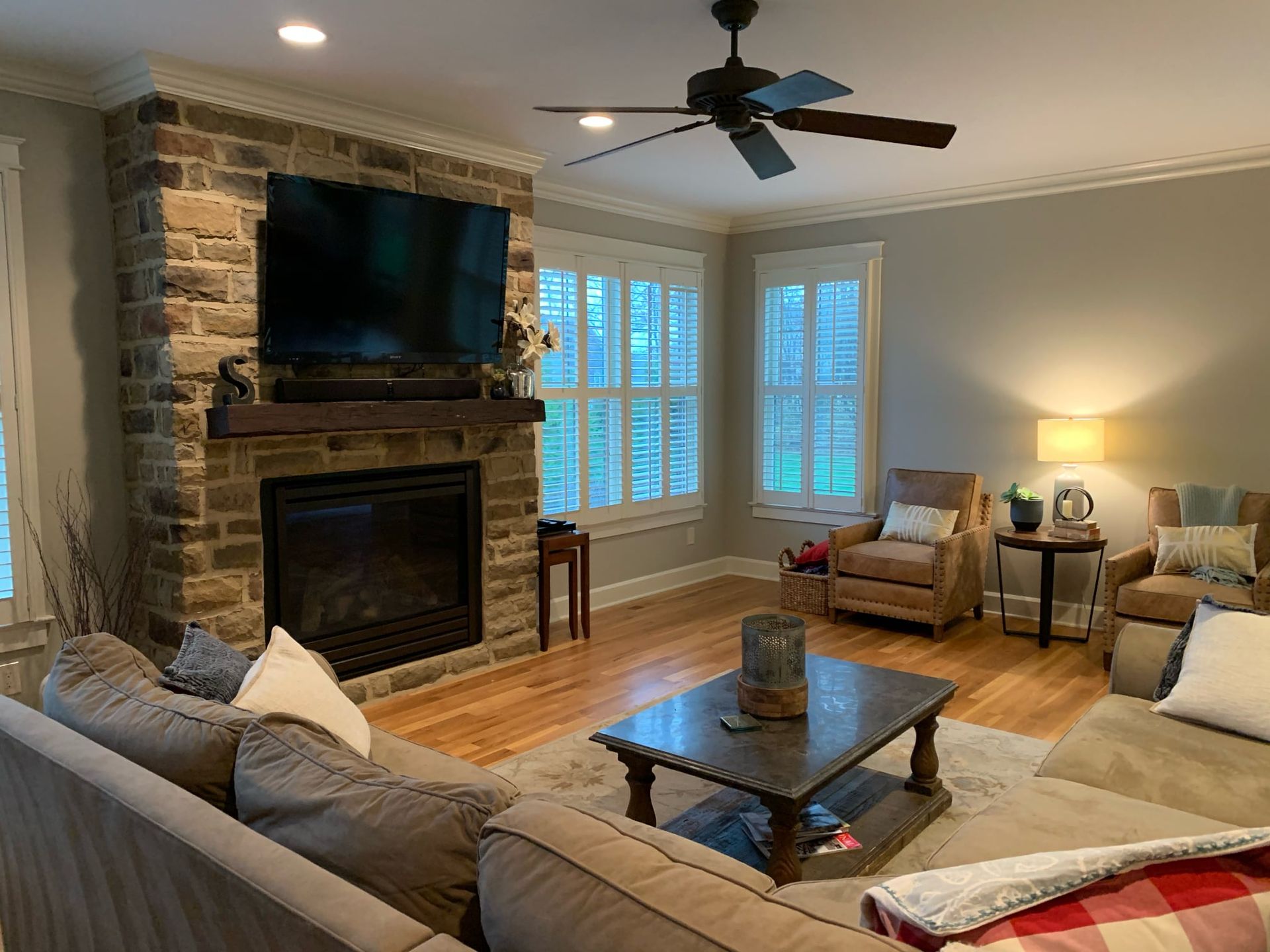 A living room with a fireplace , couch , chairs , coffee table and television.