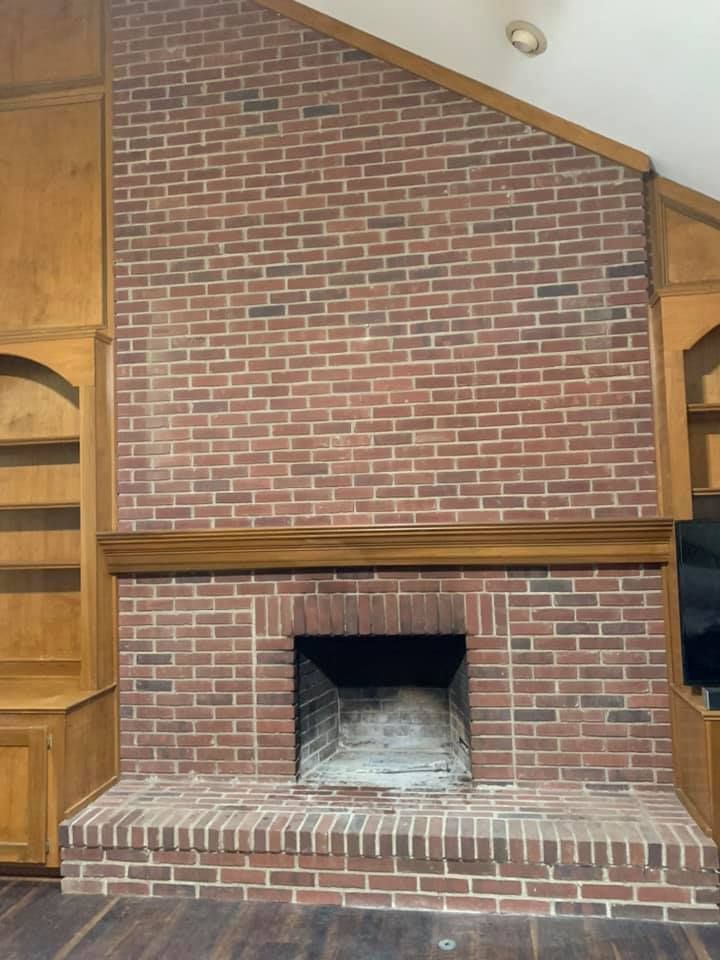 There is a brick fireplace in the middle of the room.