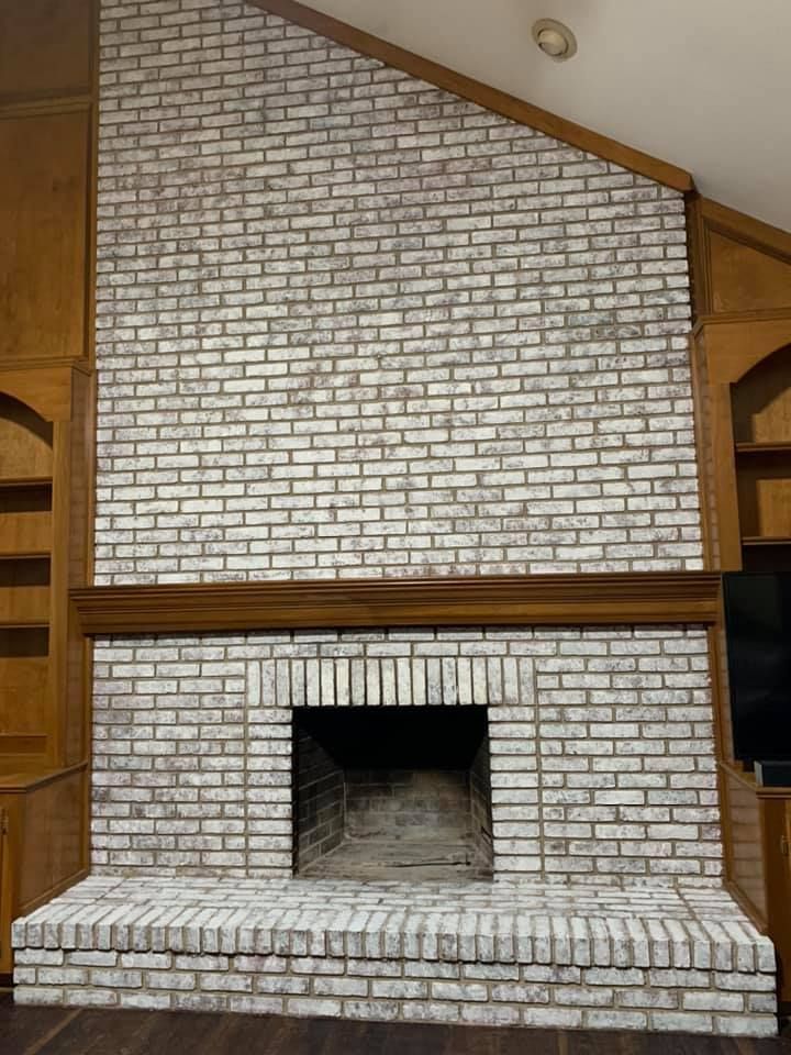 A large white brick fireplace in a living room.