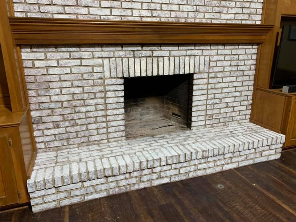A white brick fireplace with a wooden mantle in a living room.