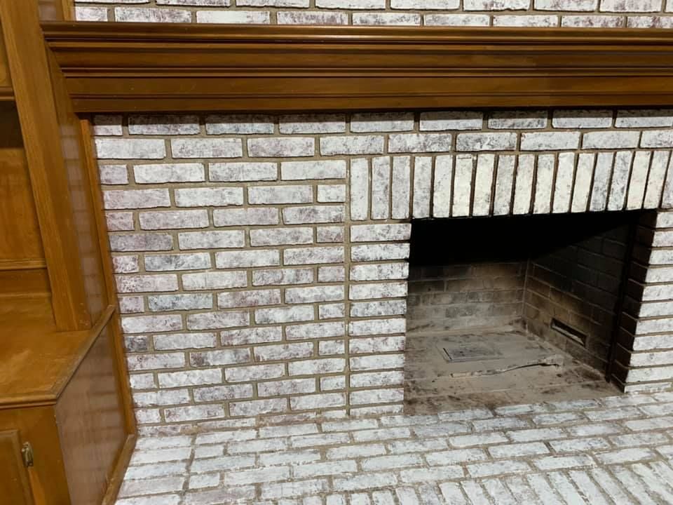 A white brick fireplace with a wooden mantle in a living room.