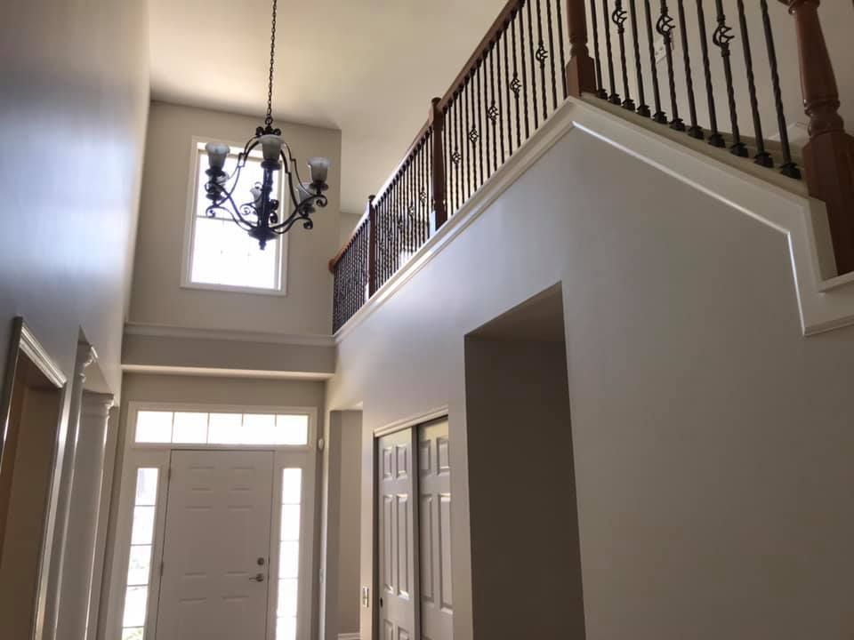 A hallway with stairs and a chandelier hanging from the ceiling.