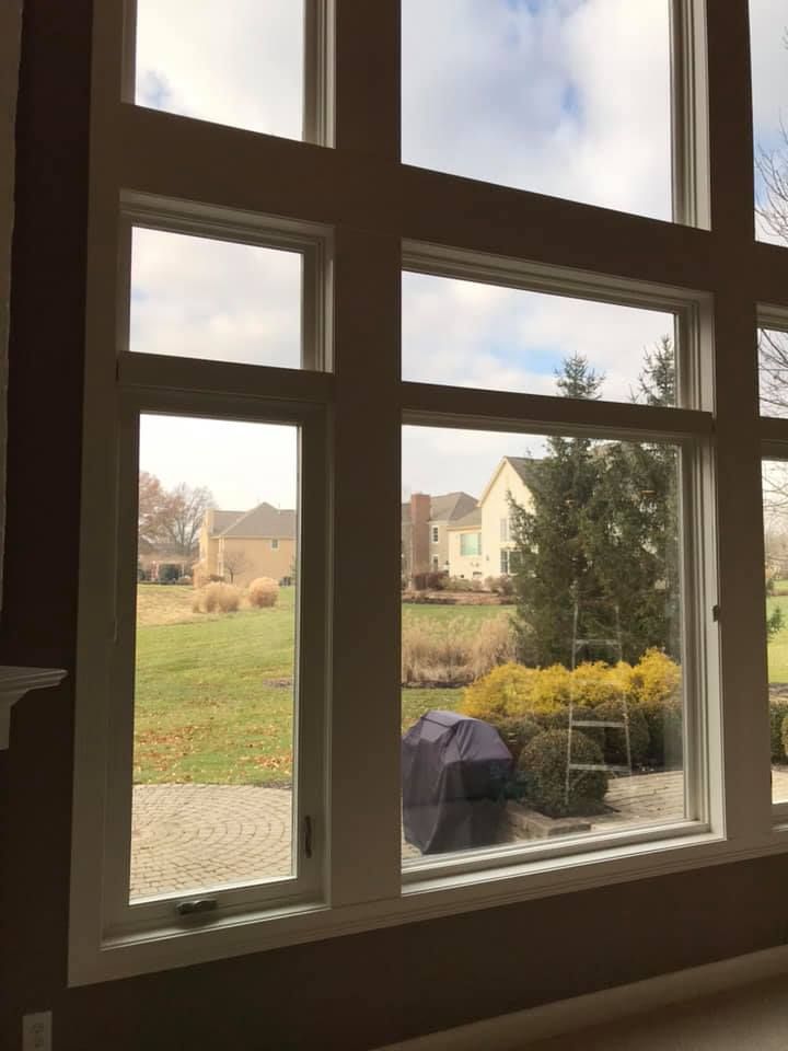 A large window with a view of a field and a house