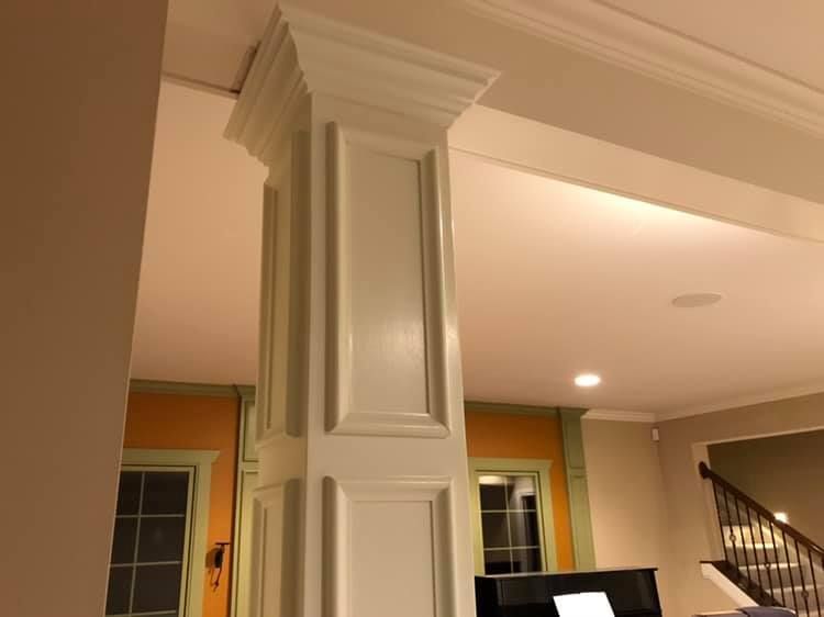 A white column in a living room next to a piano
