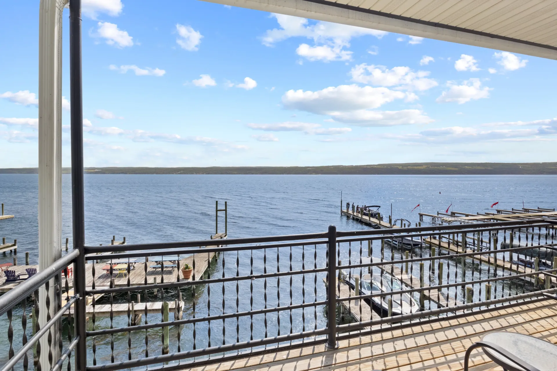 A view from a balcony looking out over a blue lake with boat docks and a partially cloudy sky.