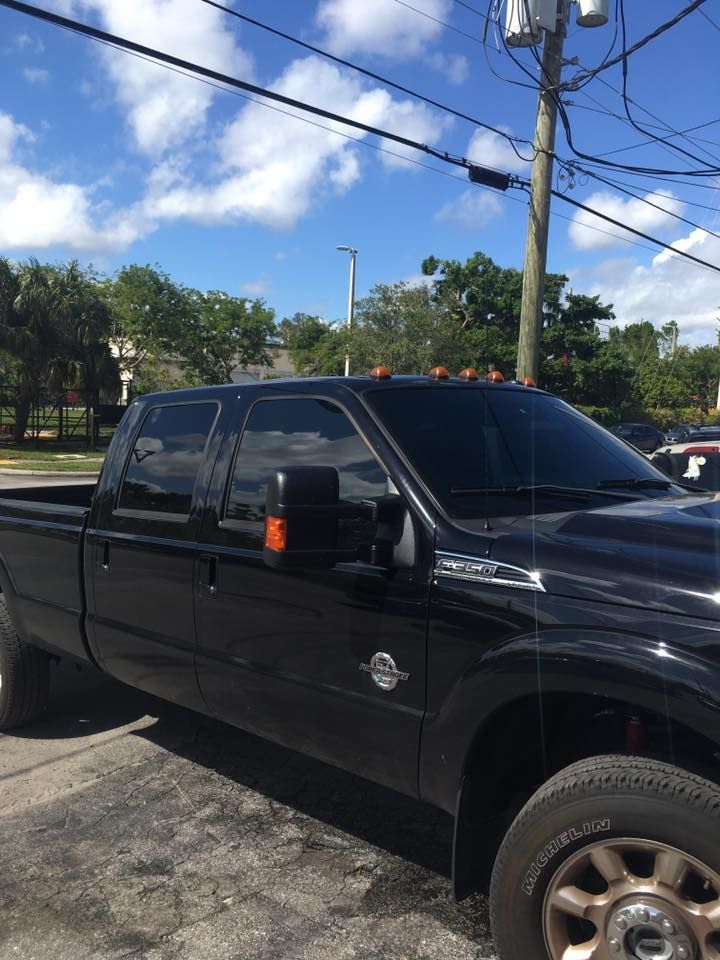 A black truck is parked in a parking lot next to a power pole.