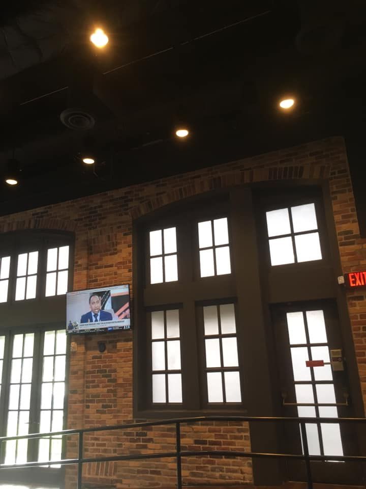 A brick wall with a tv on it and a red exit sign