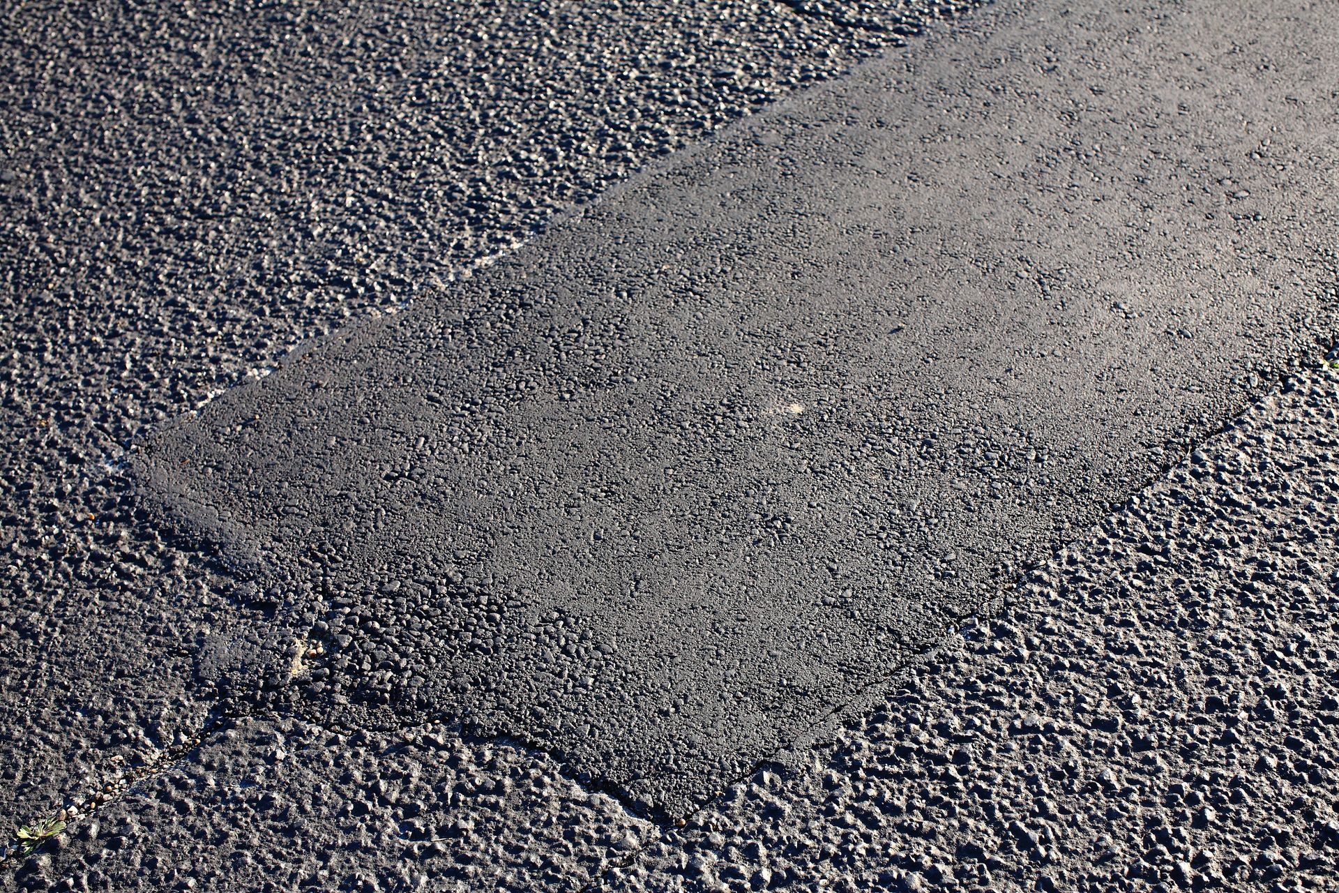 Close-up of a rough gray gravel surface with a lighter patch in the center. Close-up of a rough gray gravel surface with a lighter patch in the center.