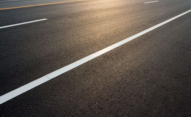Empty asphalt road with white lane markings