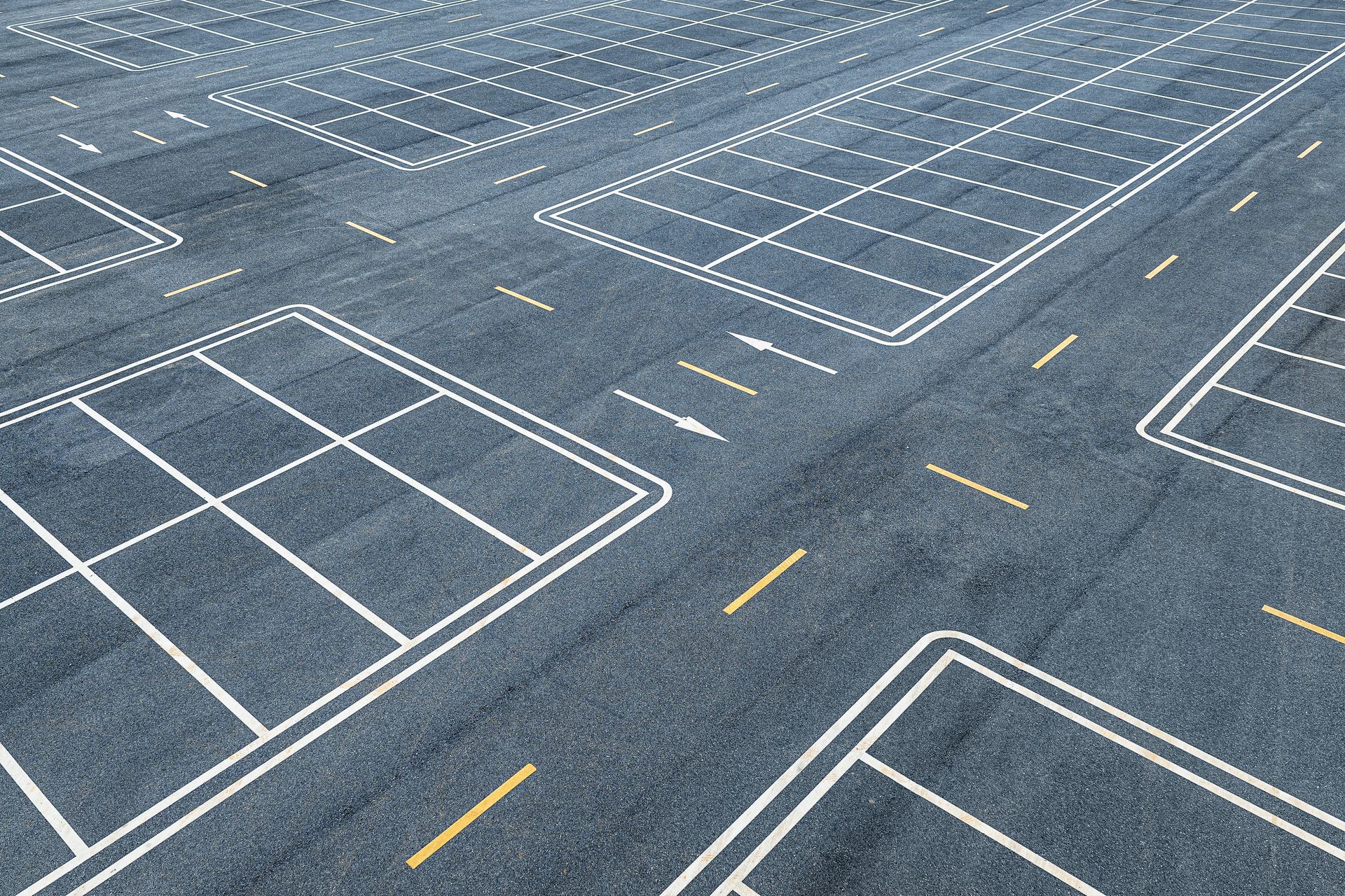 Empty parking lot with white marked spaces and yellow lane lines on dark asphalt. Empty parking lot with white marked spaces and yellow lane lines on dark asphalt.