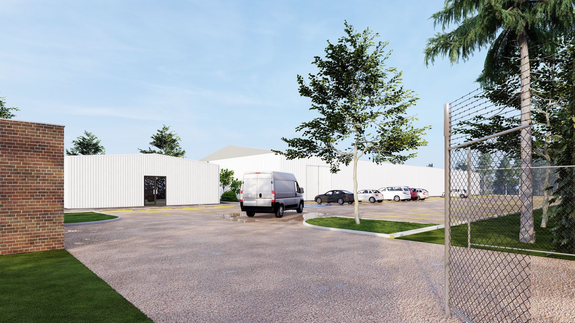 Gravel lot beside white storage buildings, with parked trucks, trees, and a chain-link fence.