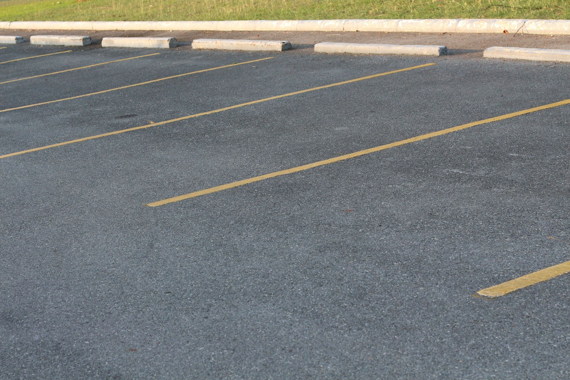 Empty parking lot with yellow painted lines and curb stops on gray asphalt. Empty parking lot with yellow painted lines and curb stops on gray asphalt.
