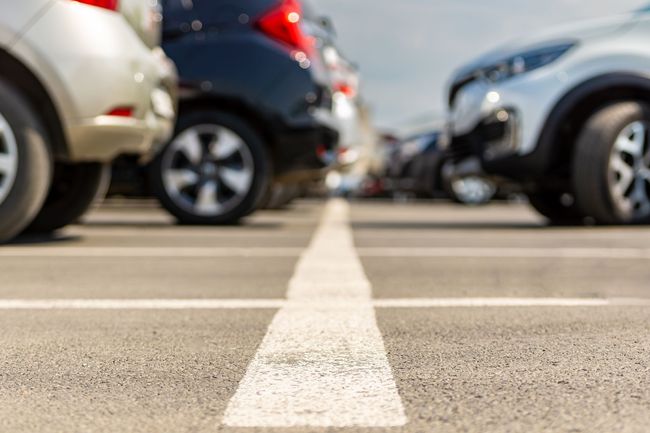 Low-angle view of parked cars lined up in a parking lot with a white center line. Low-angle view of parked cars lined up in a parking lot with a white center line.