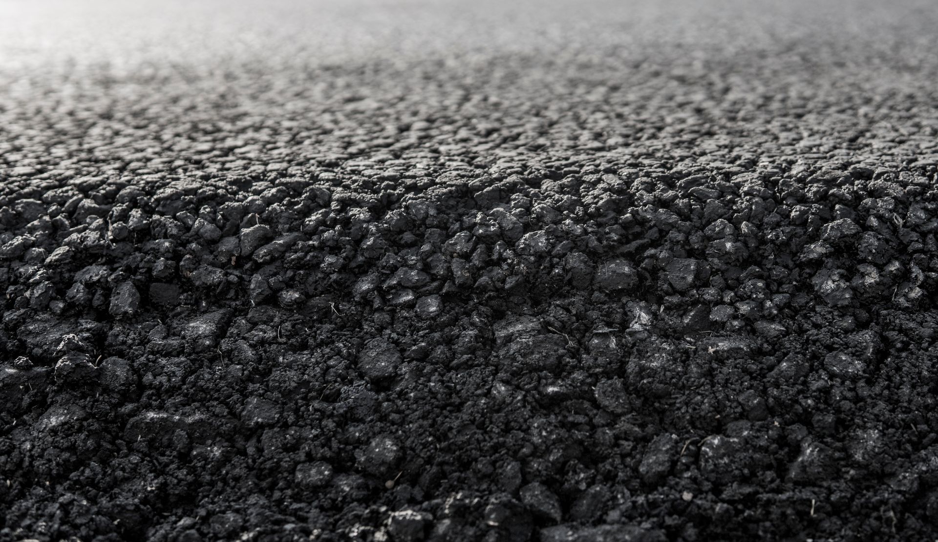 Close-up of rough black asphalt texture with small reflective stones