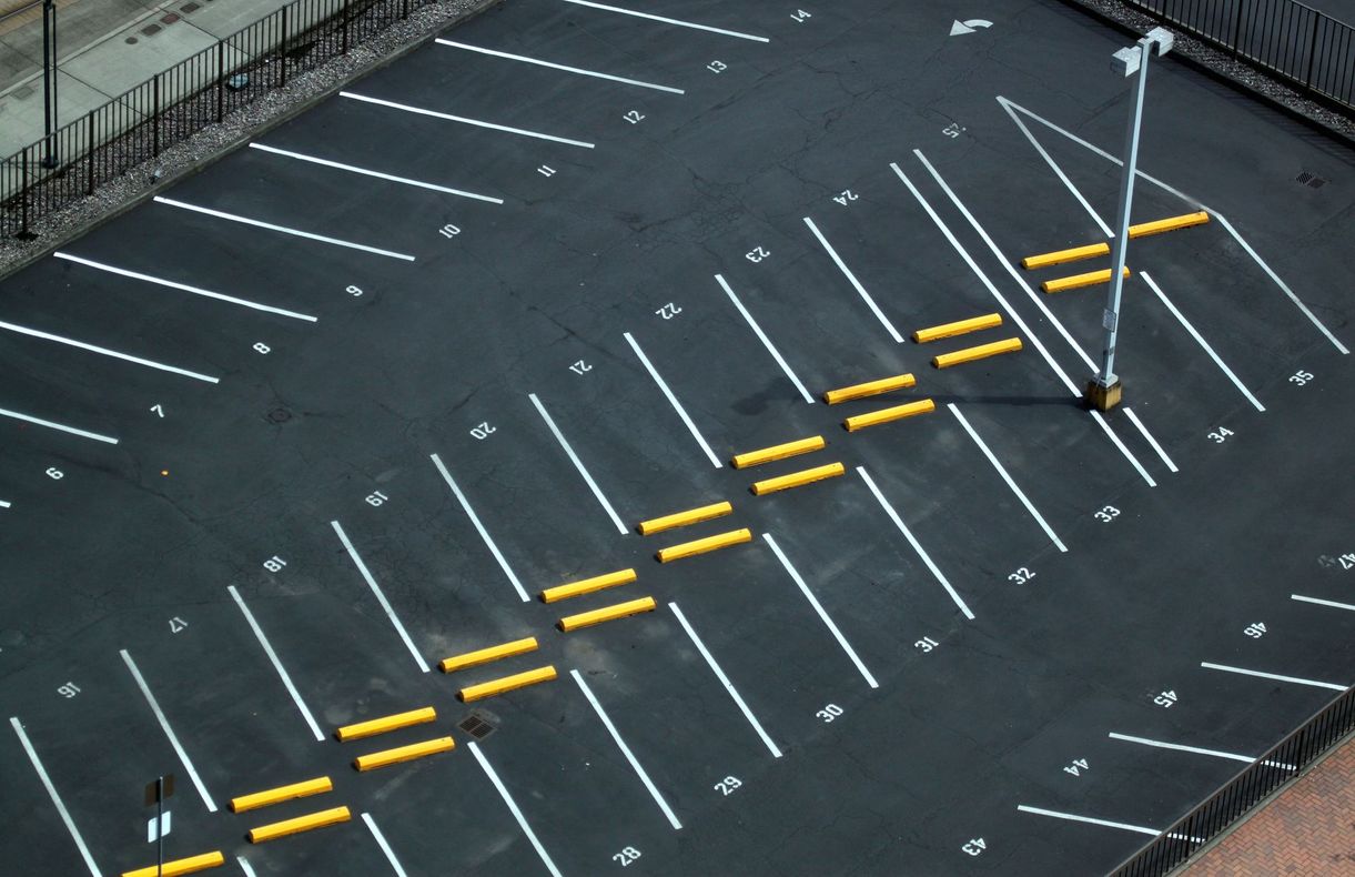 Aerial view of an empty parking lot with yellow zigzag lane markings and white parking spaces.