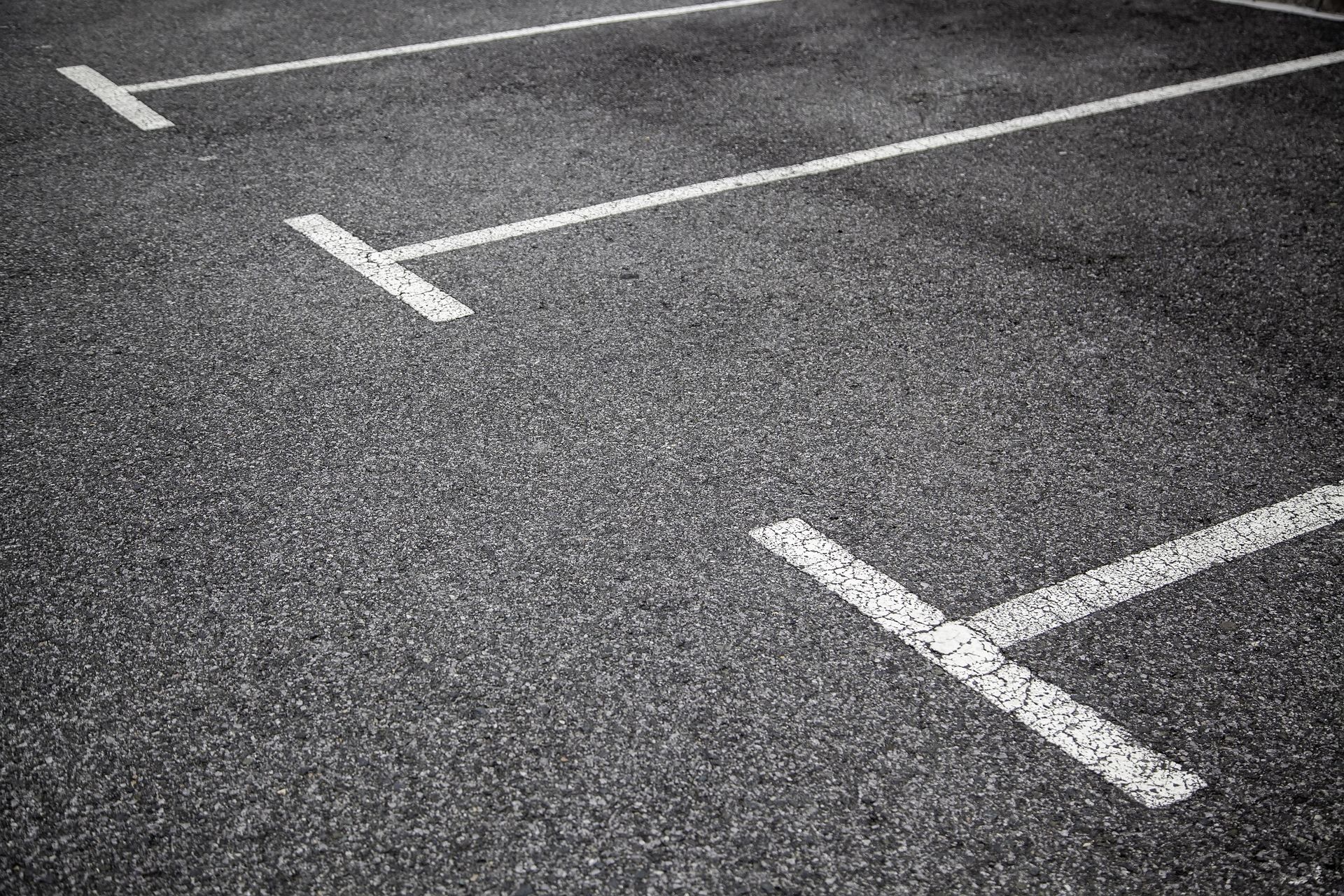 Empty parking lot with white painted parking space lines on dark asphalt.