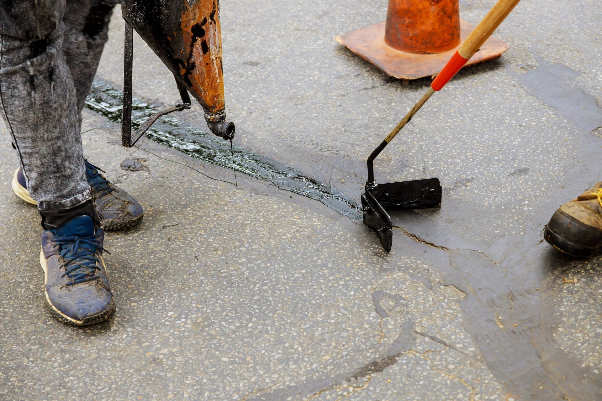 Workers smoothing wet concrete with a trowel around orange traffic cones