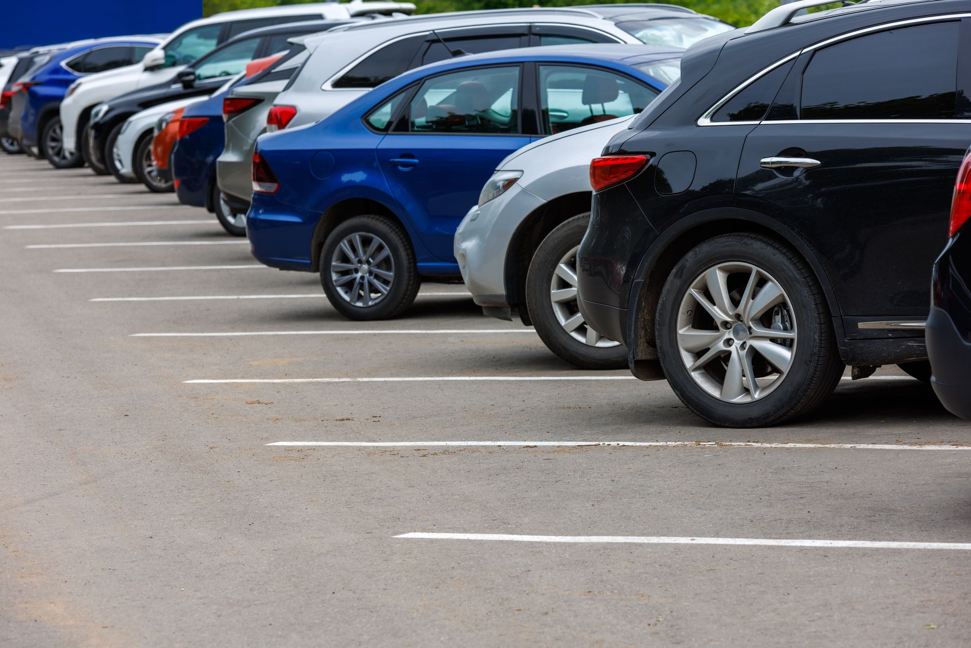 Row of parked cars in a parking lot, including blue, white, and black vehicles. Row of parked cars in a parking lot, including blue, white, and black vehicles.